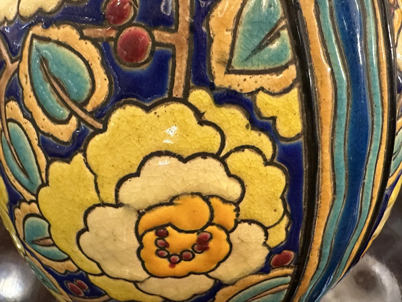 Cerâmica antiga com decoração floral colorida em amarelo e azul sobre fundo azul claro.