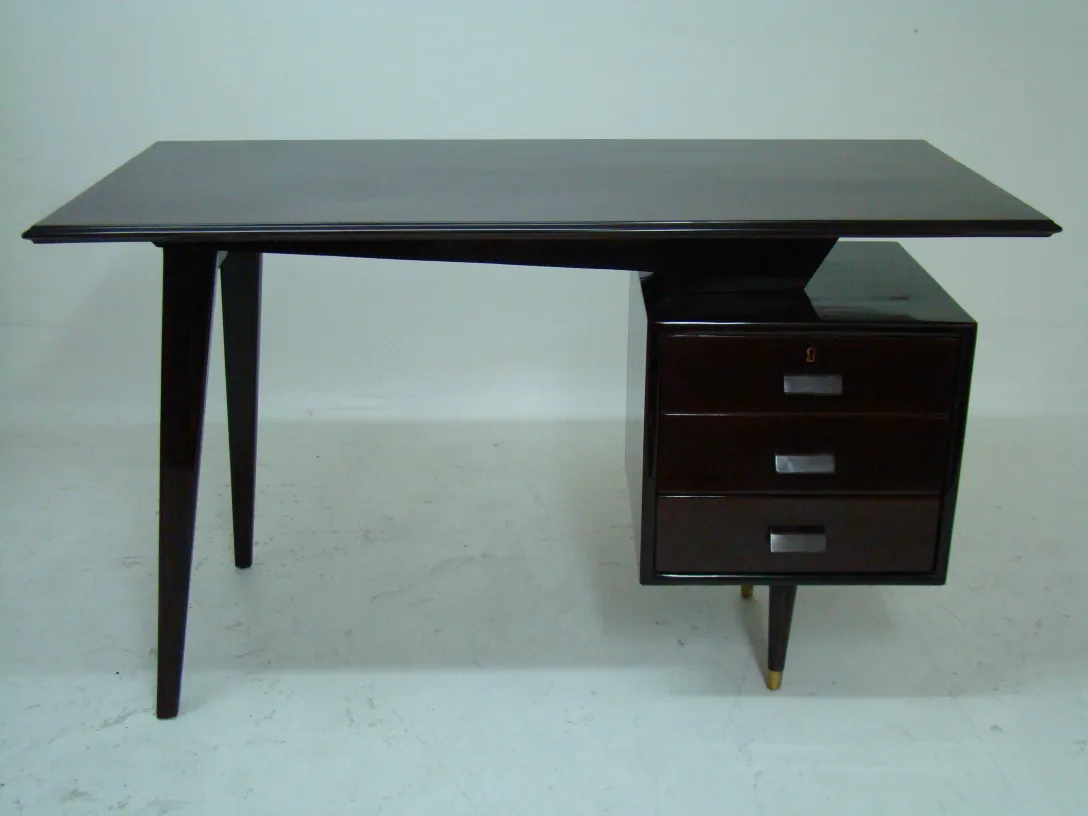 Antique desk with two drawers and slim legs, in a simple setting.