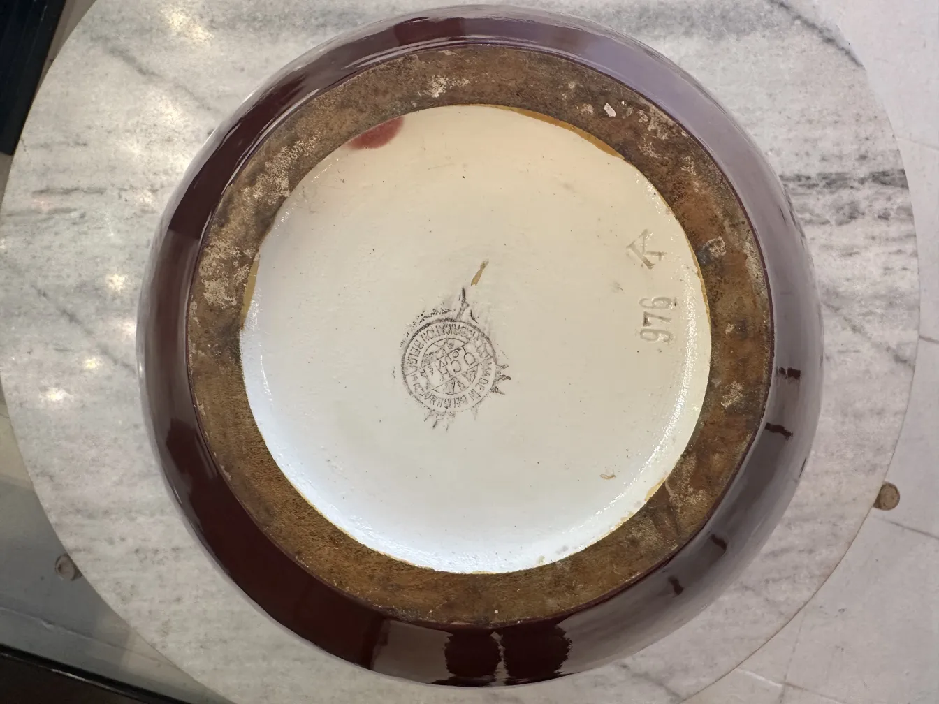 Draufsicht auf eine antike Keramikschüssel mit brauner Glasur auf einer Marmoroberfläche.