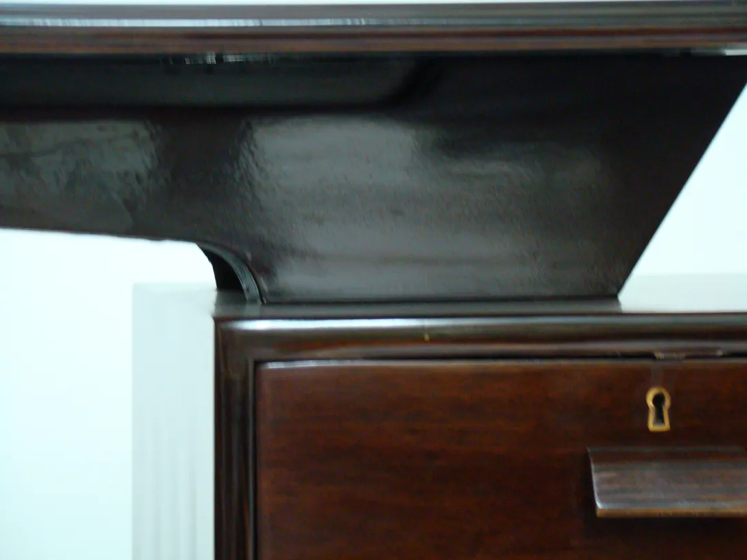 Vue rapprochée d'un bureau ancien en bois avec un design élégant et une finition brillamment polie, sans distractions.