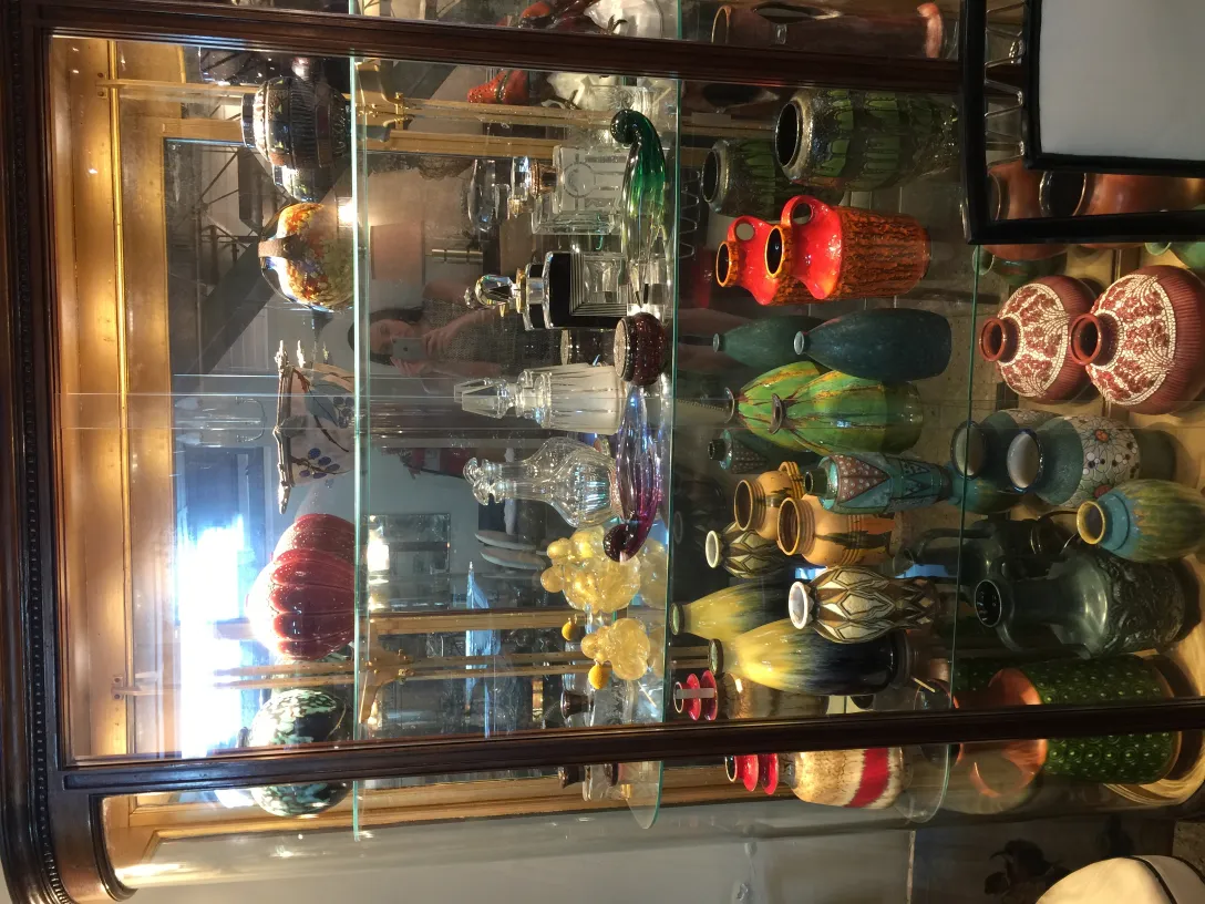 さまざまな色と形の古い装飾的な陶器を展示するケース