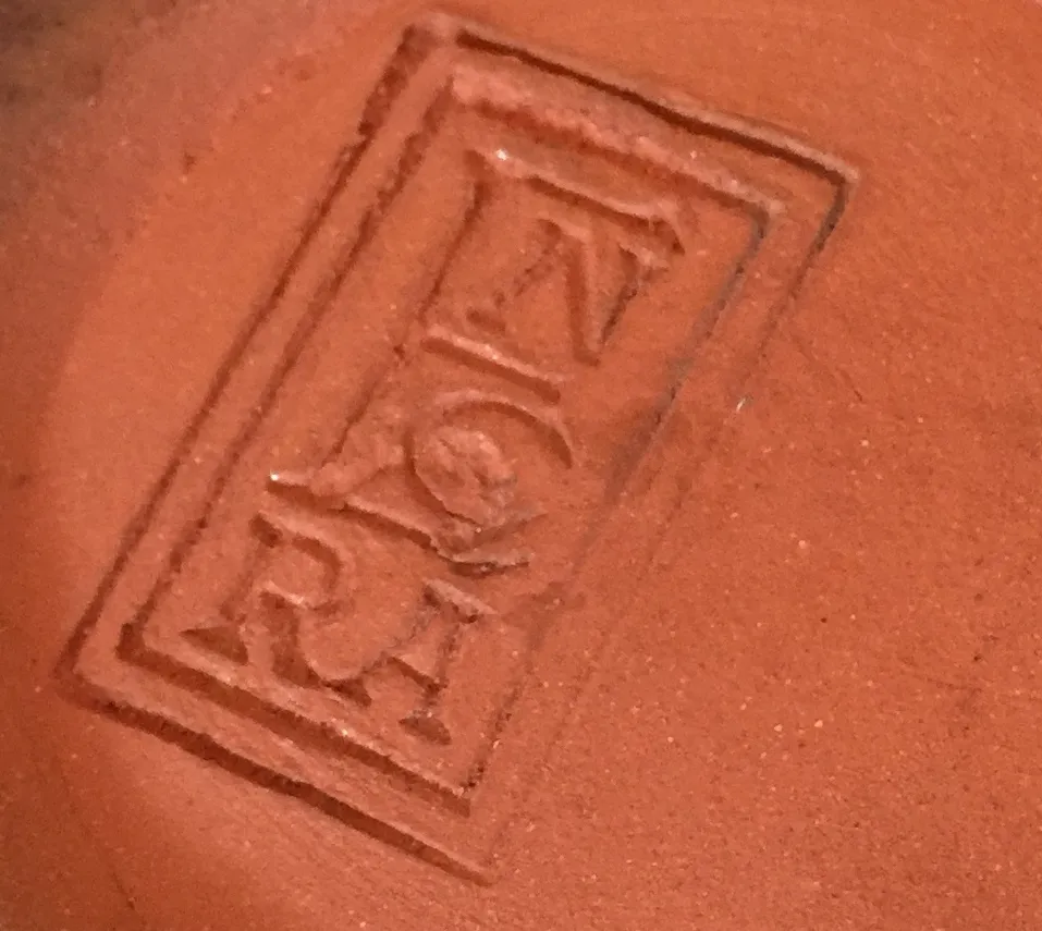 Antique ceramic with inscription, terracotta color, smooth background.