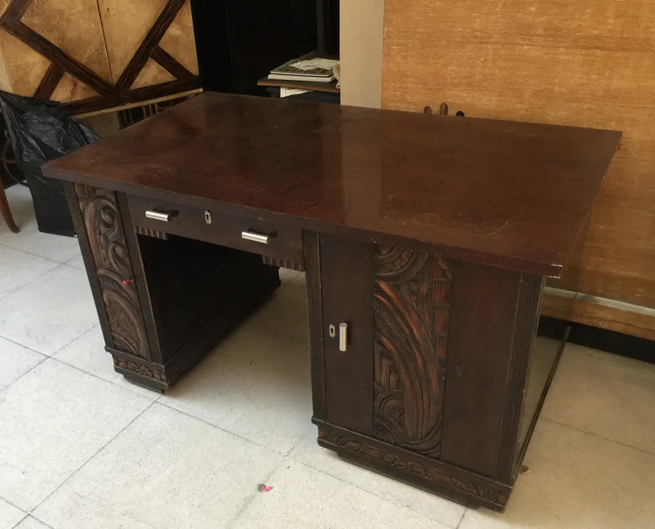 Antique wooden desk with intricate carvings on the sides, neutral background.