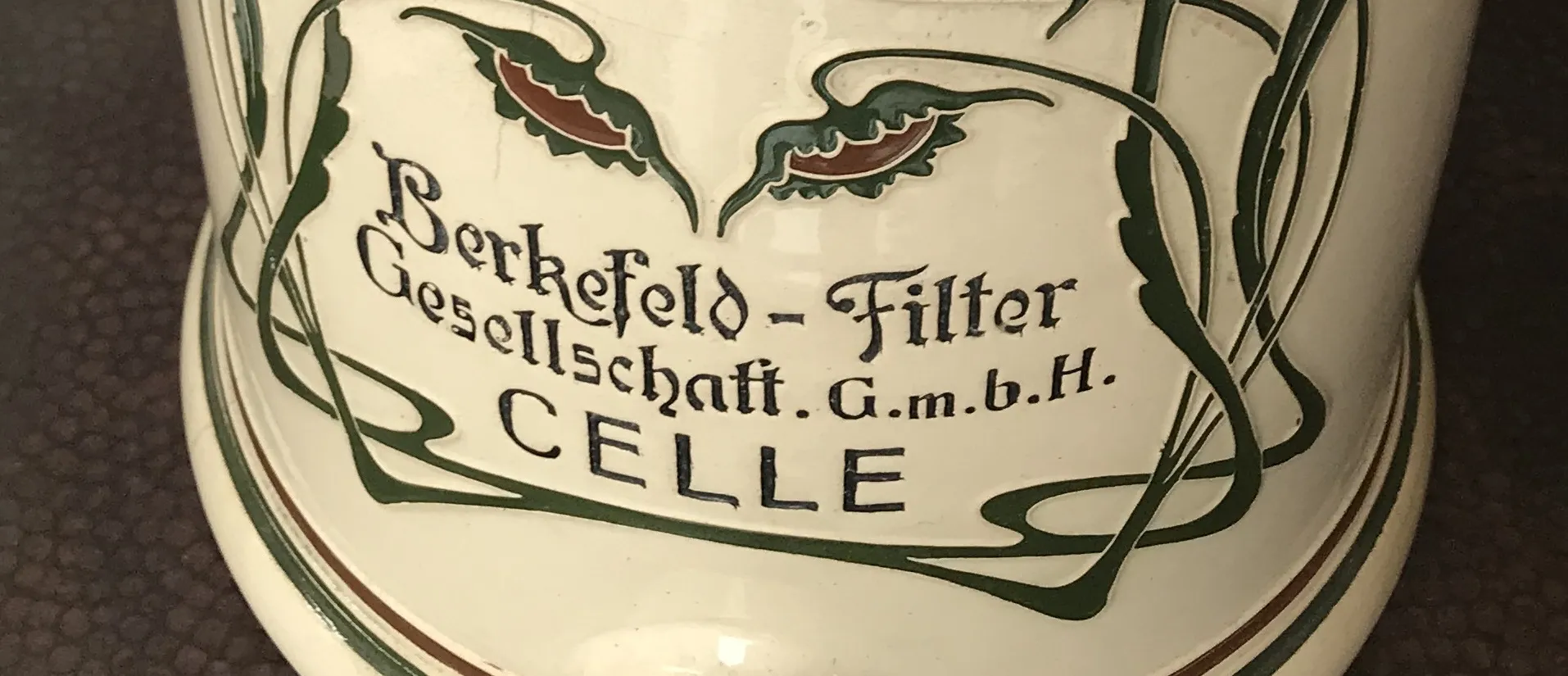 Ancienne céramique de Berkefeld avec décoration florale en vert et rouge.