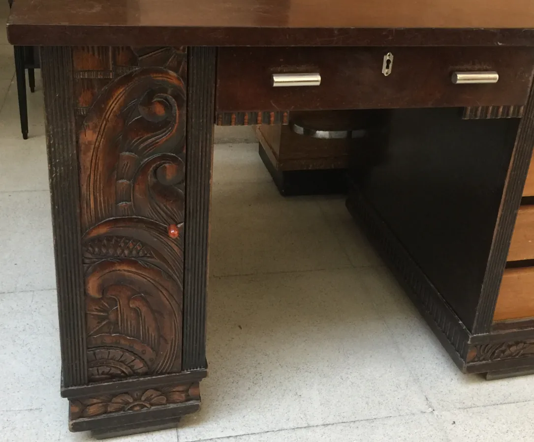 Escritorio antigo com entalhes ornamentais na lateral.