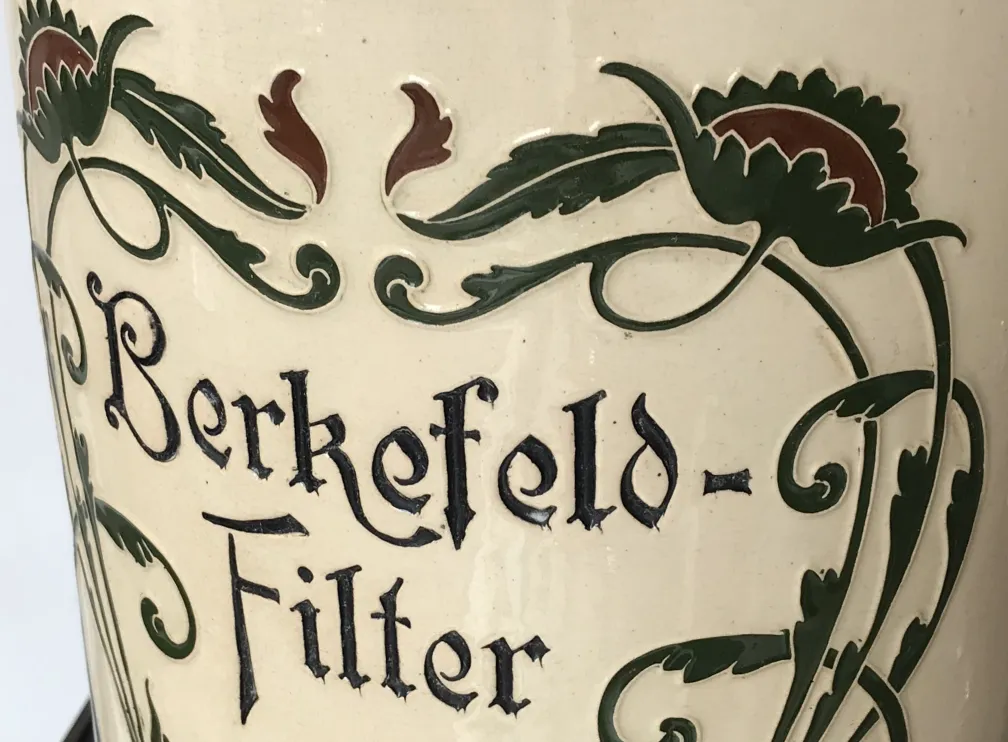 Antiga cerâmica Berkefeld com padrão floral escuro.