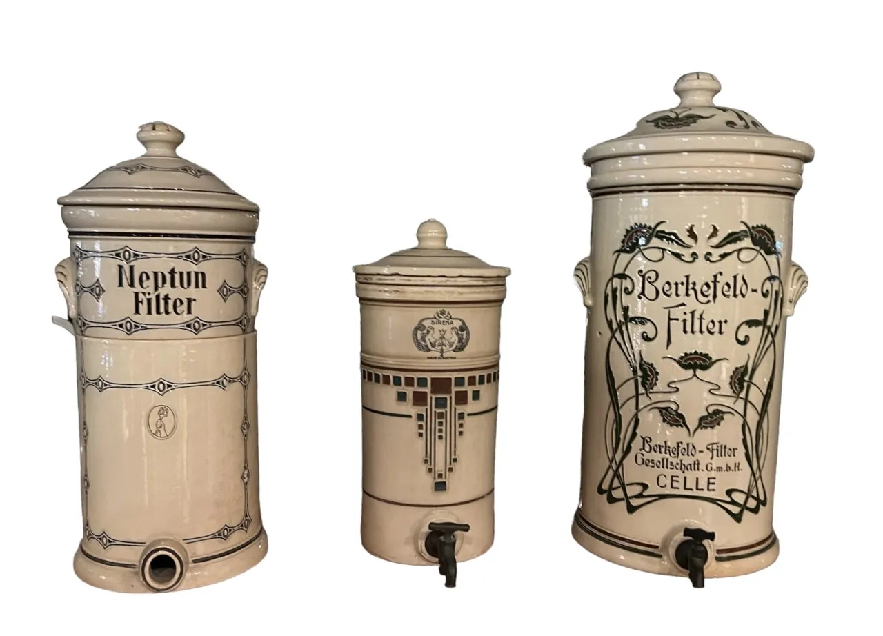 Three antique ceramic water filters with decorative designs.