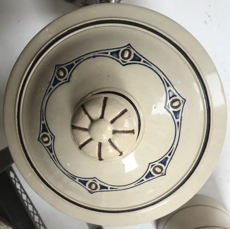円形の古代の陶器の蓋に青いディテールが施されており、エレガントで装飾的です。