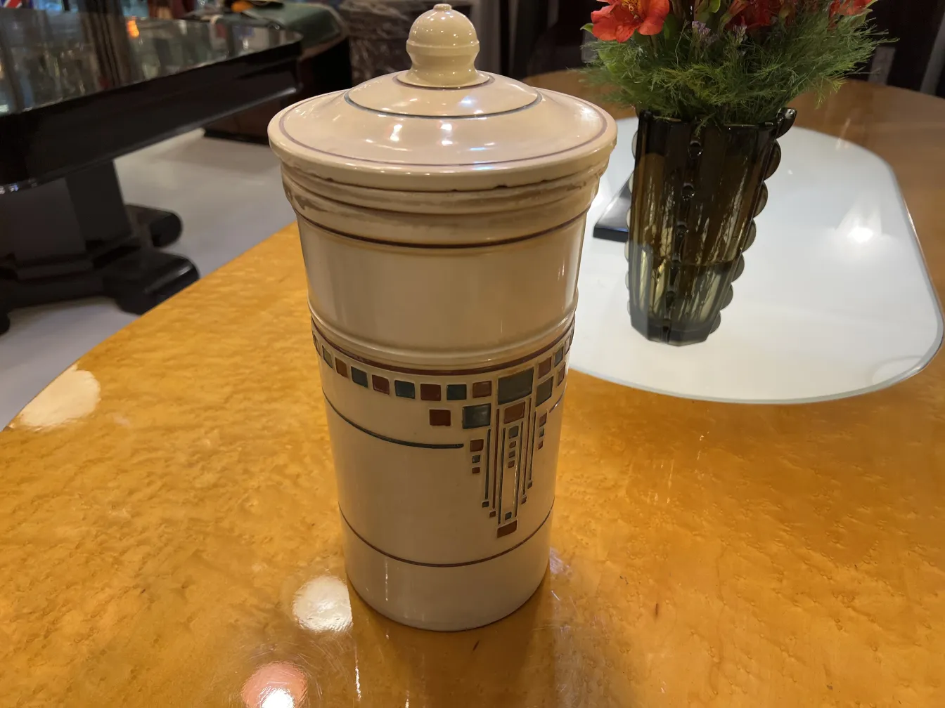 고풍스러운 장식 세라믹, 흰색 표면에 디자인이 있으며, 노란색 테이블 위에 있습니다.