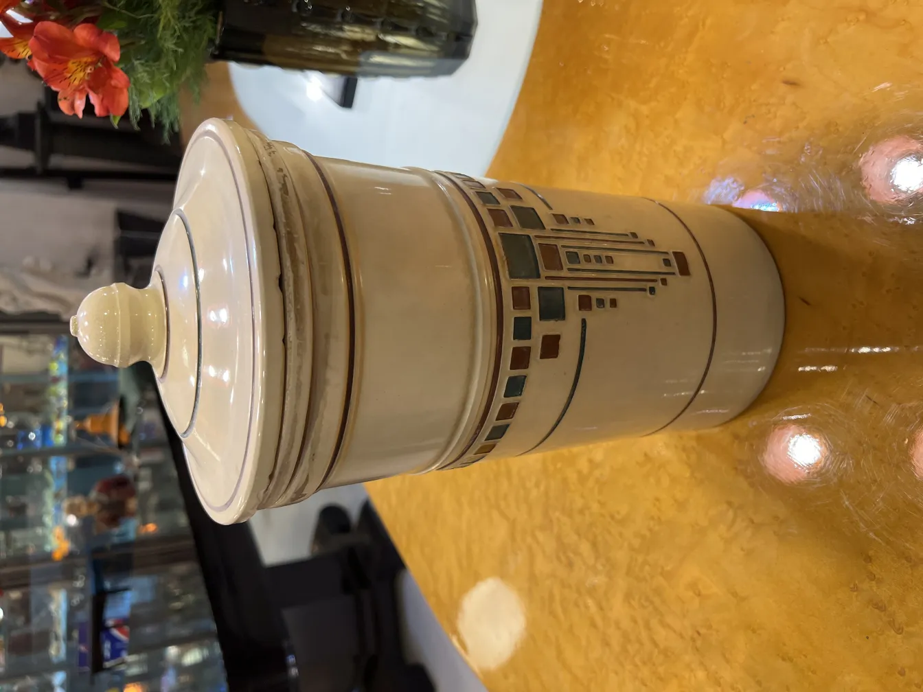 Антикварная керамика с декорированной крышкой и детализированными узорами, окруженная цветами.