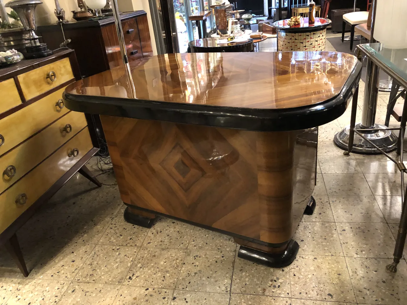 Escritorio antiguo con superficie brillante y acabado elegante, rodeado de muebles vintage.