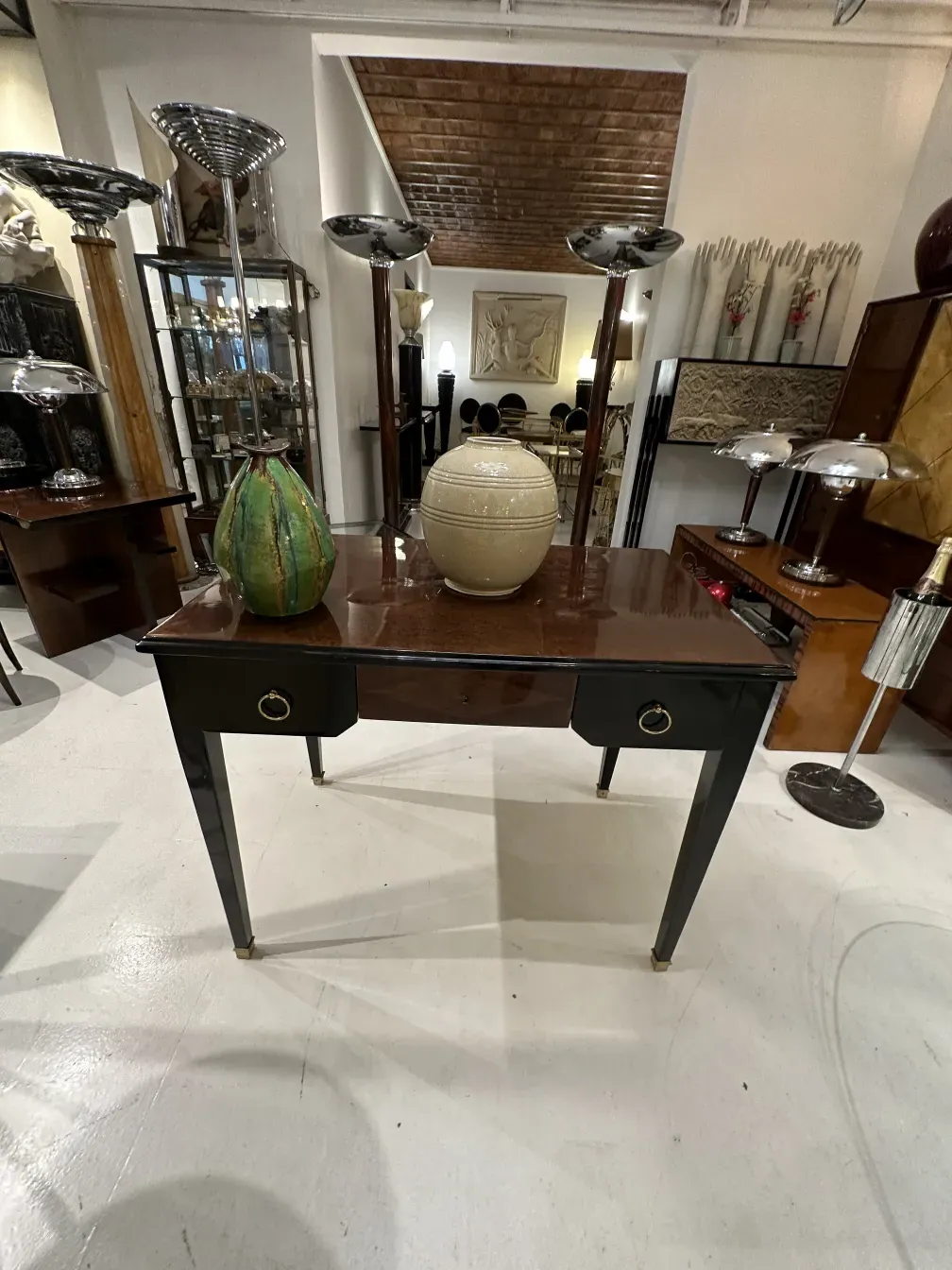 Bureau ancien avec une finition brillante et des accents dorés, décoré d'accessoires modernes.