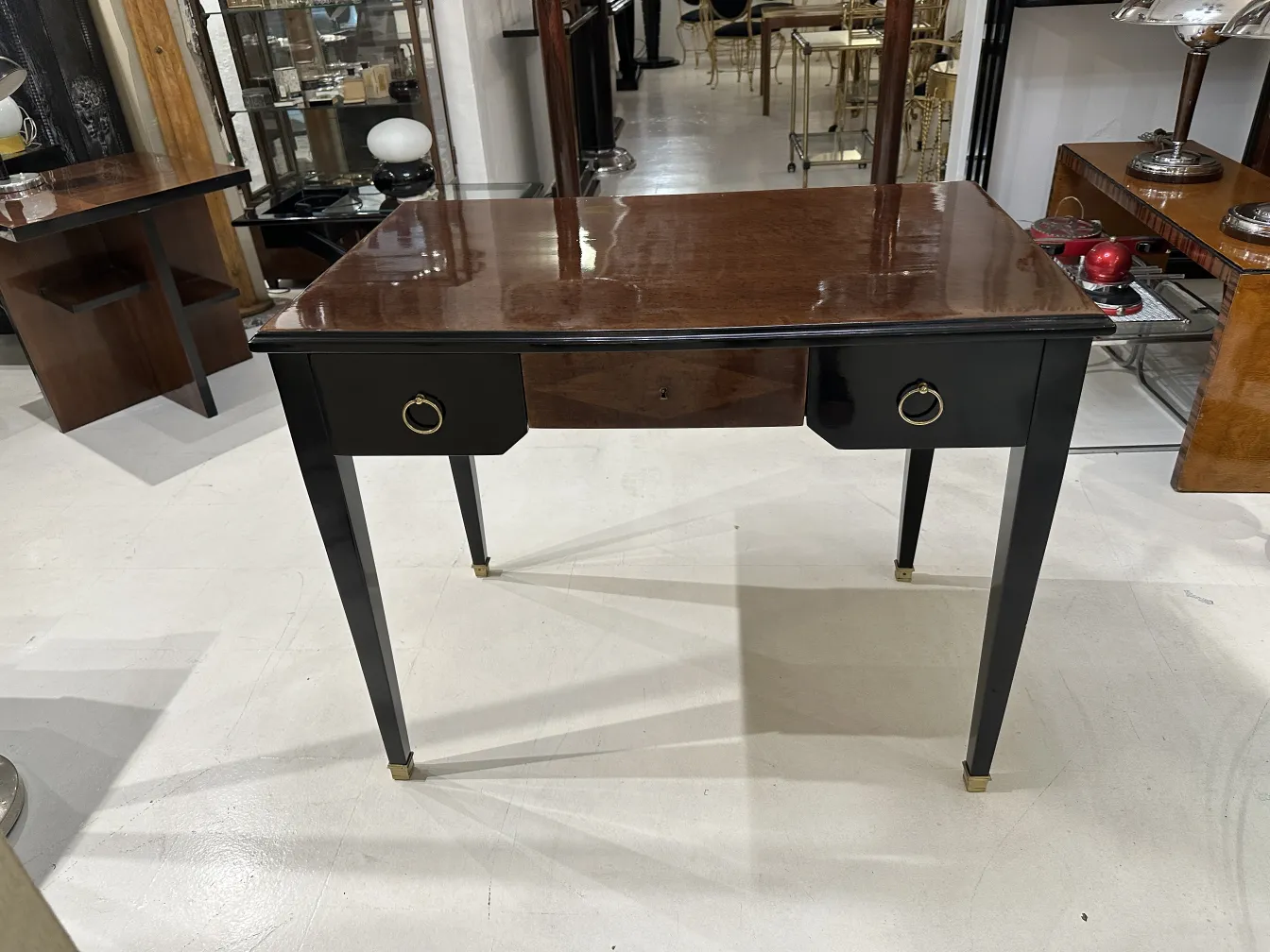 escritorio antiguo con un acabado brillante, cajón frontal y otros muebles al fondo