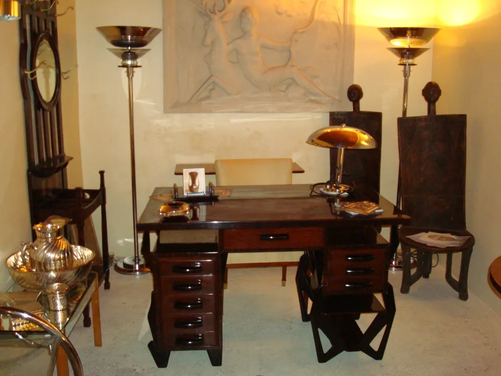 Antiker Holzschreibtisch in eleganter Umgebung mit Lampe und Stühlen.