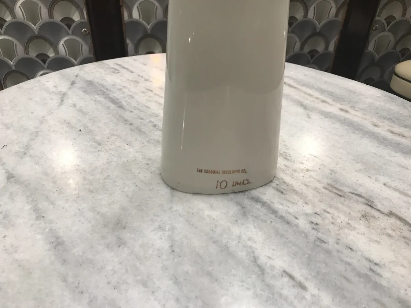 Ceramica antica con dettaglio di base visibile, su sfondo chiaro.