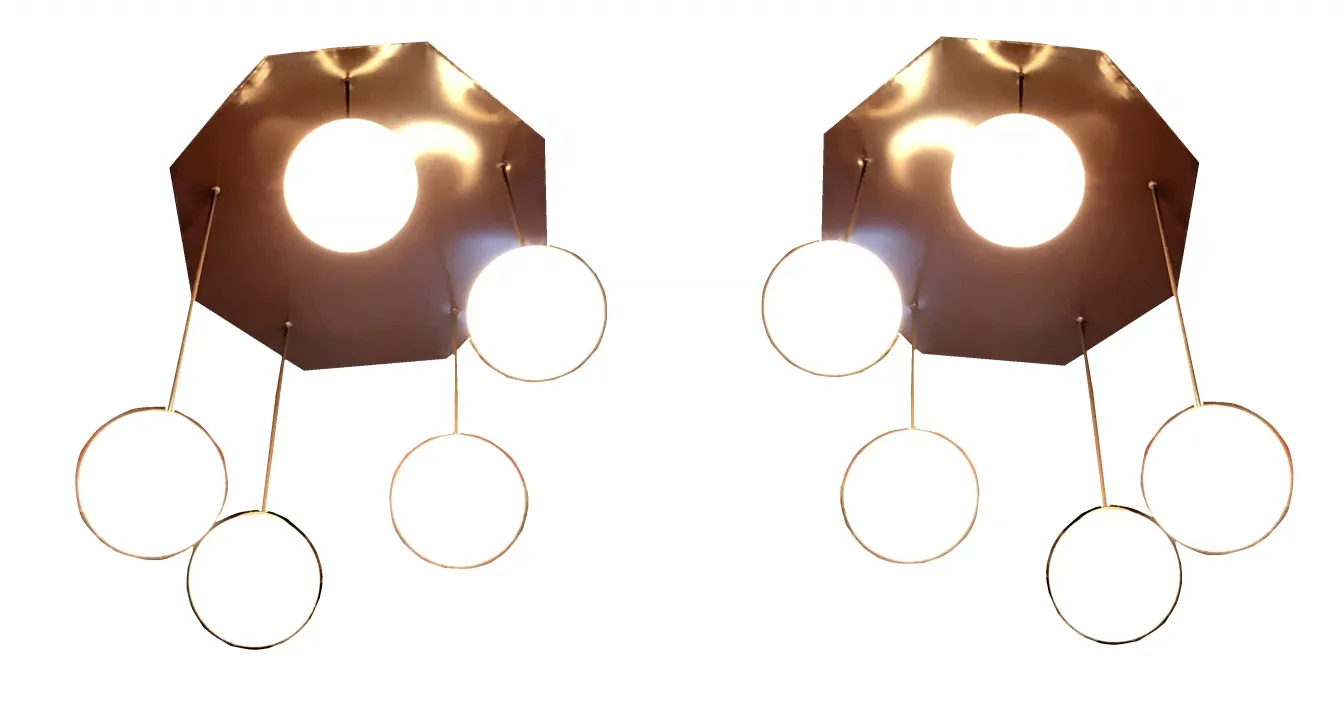 Quattro lampade a sospensione antiche con design circolare, che illuminano uno spazio moderno.