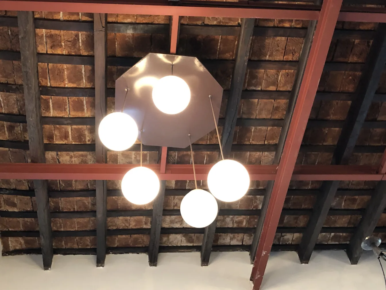 Four contemporary design hanging lamps from a wooden ceiling.