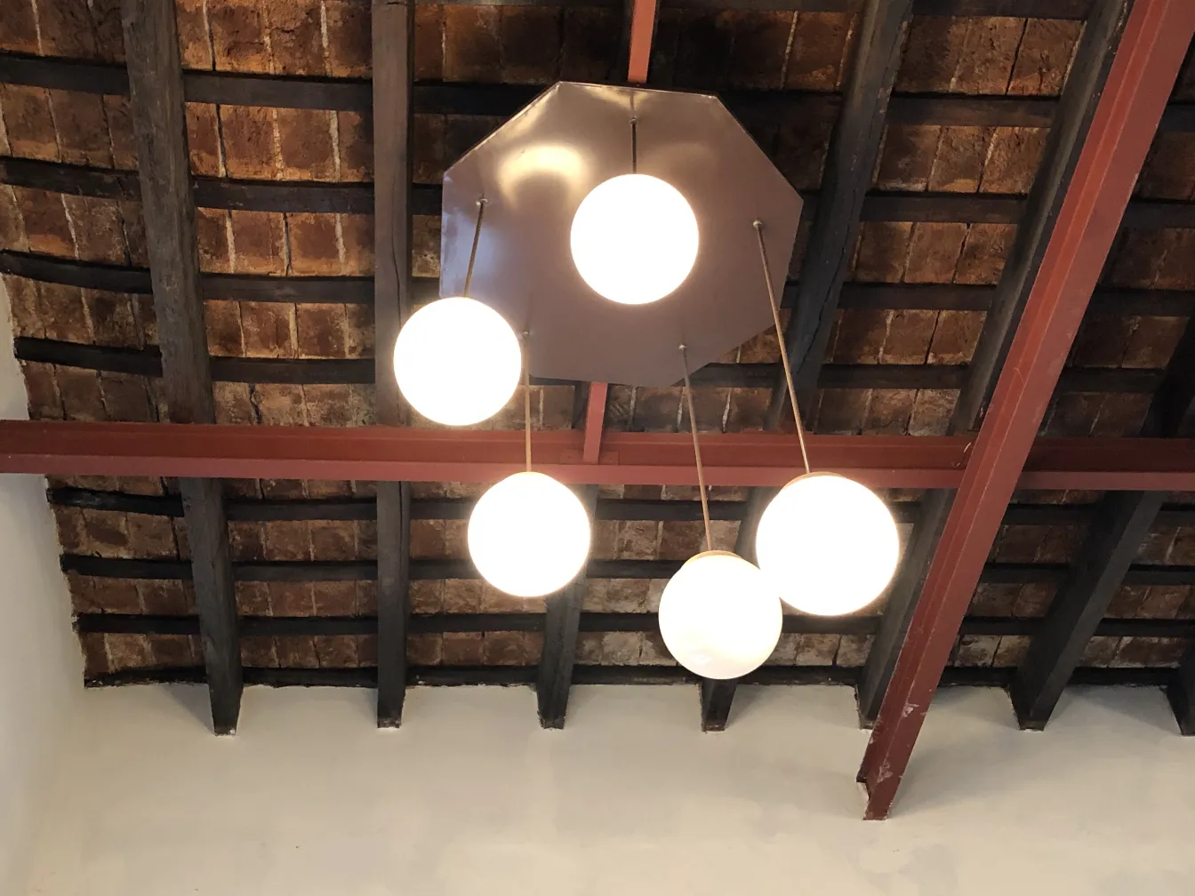 Four antique hanging lamps with white globes in a rustic setting.