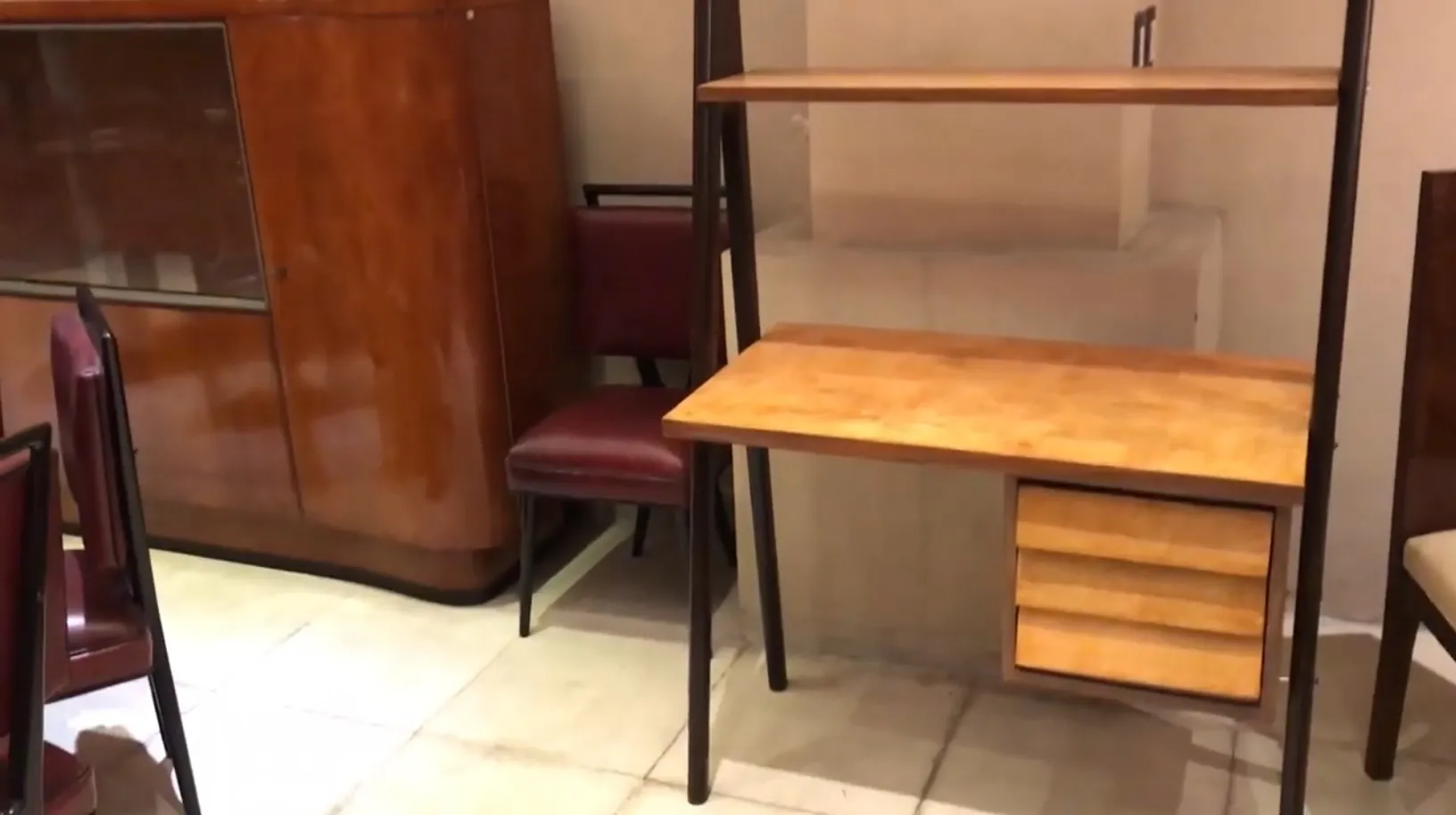 Bureau ancien en bois avec étagères et tiroirs. Ambiance confortable avec des chaises.