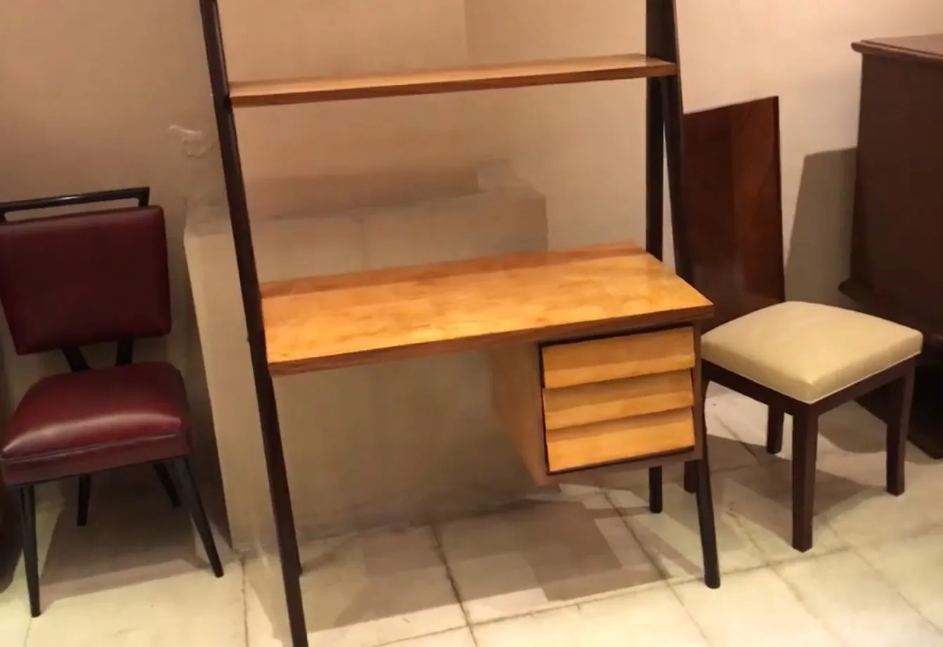 Scrivania antica in legno con ripiano e cassetti, ambiente accogliente.