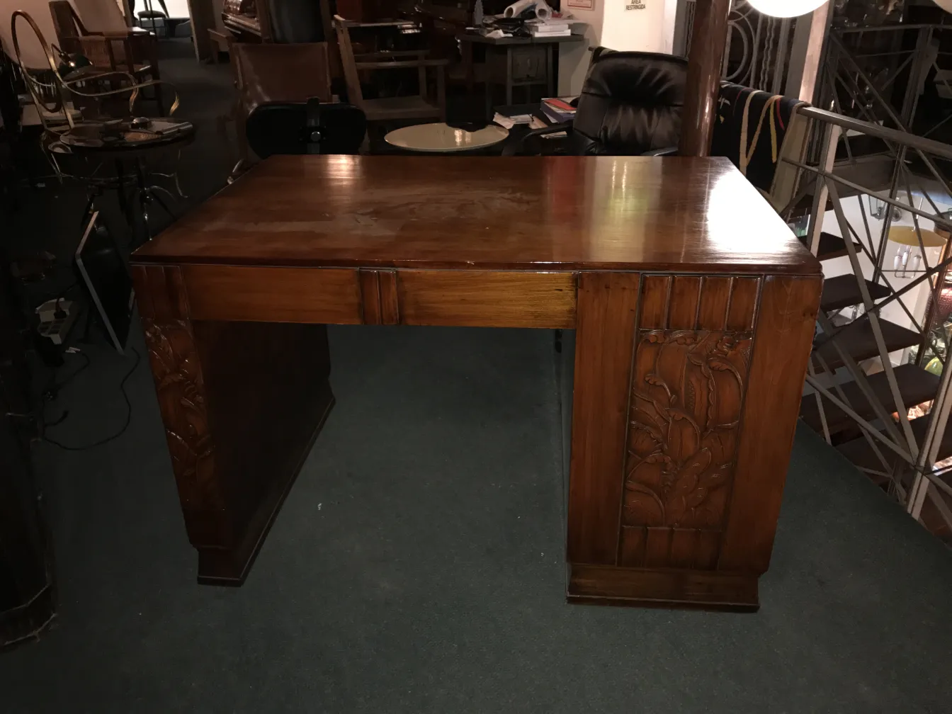 Escritorio antiguo de madera con detalles tallados, en un ambiente de mostrador