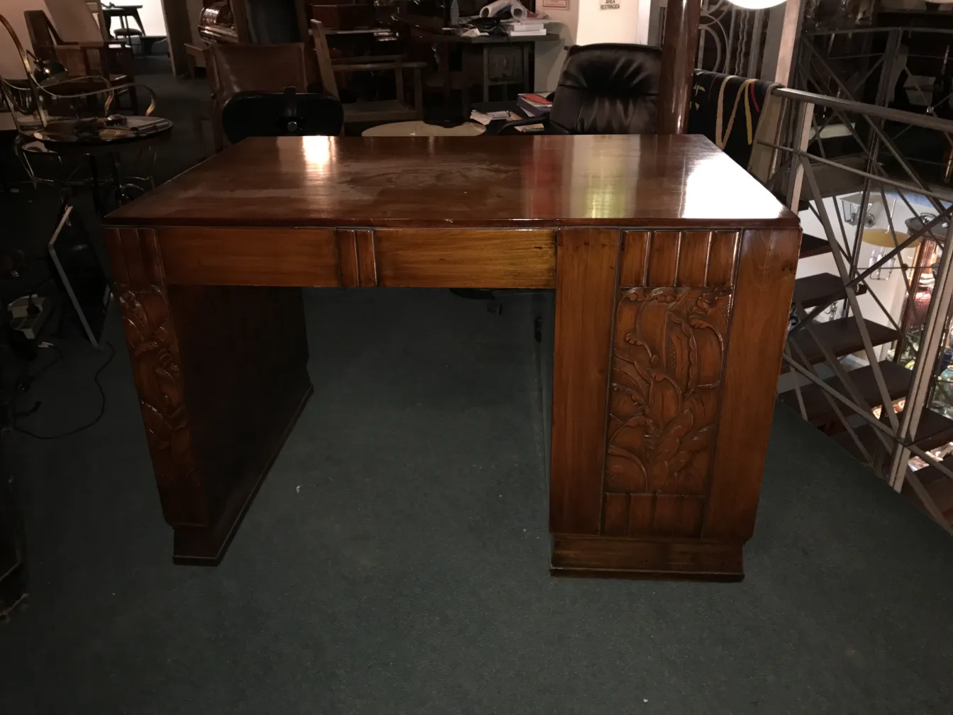 Antique wooden desk with carved details, cozy environment.