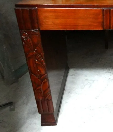 escritorio antiguo con detalles tallados en las patas, fondo neutro.