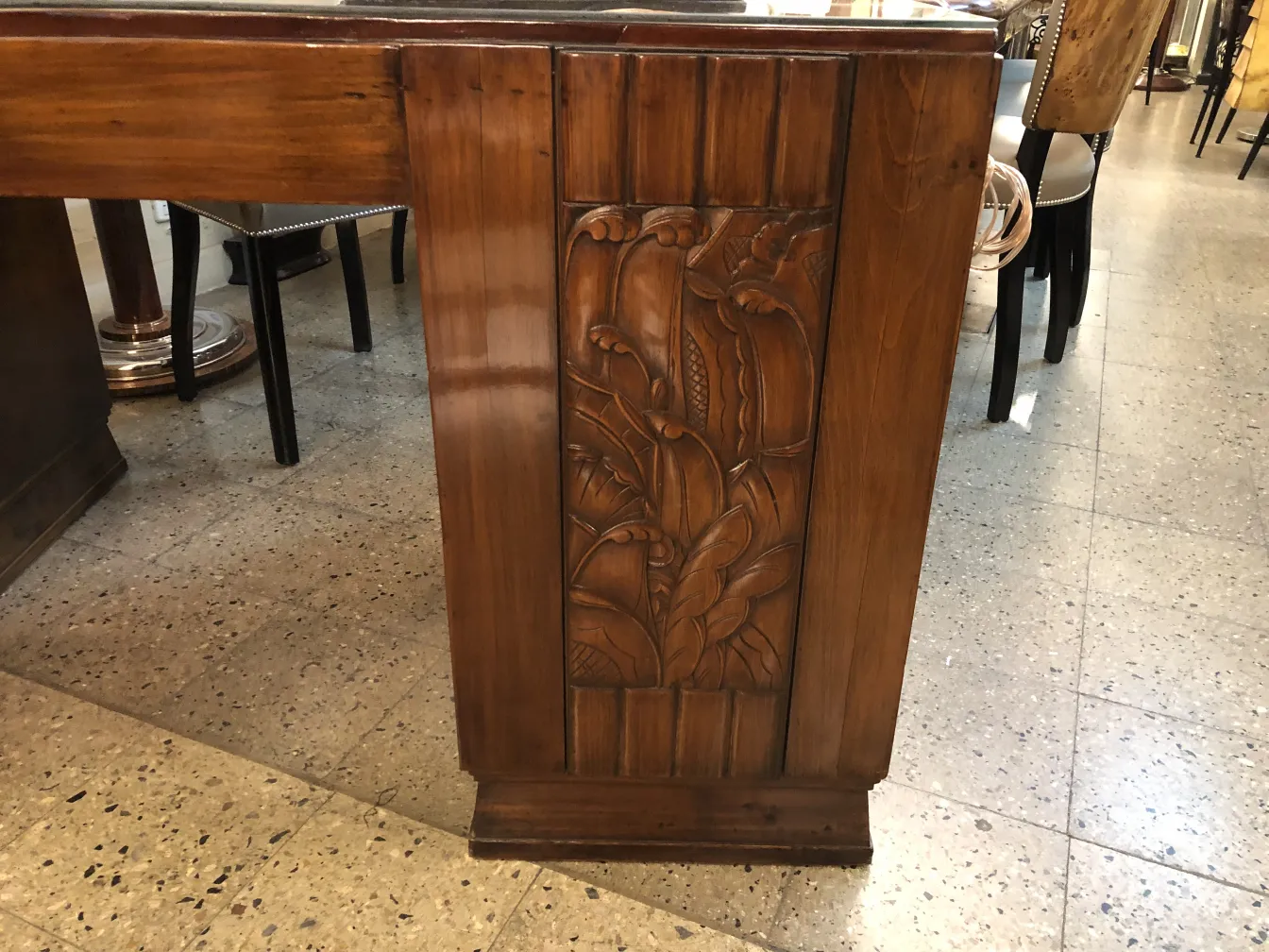 Antiker Holzschreibtisch mit dekorativen Reliefs an der Seite, warme Atmosphäre.