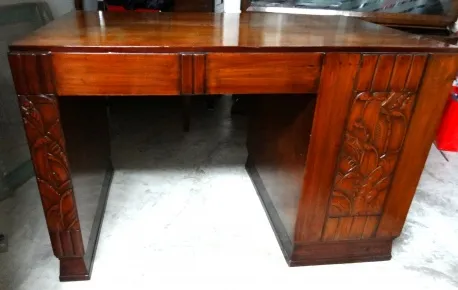 Scrivania antica in legno con dettagli decorativi sui lati e finitura lucida.