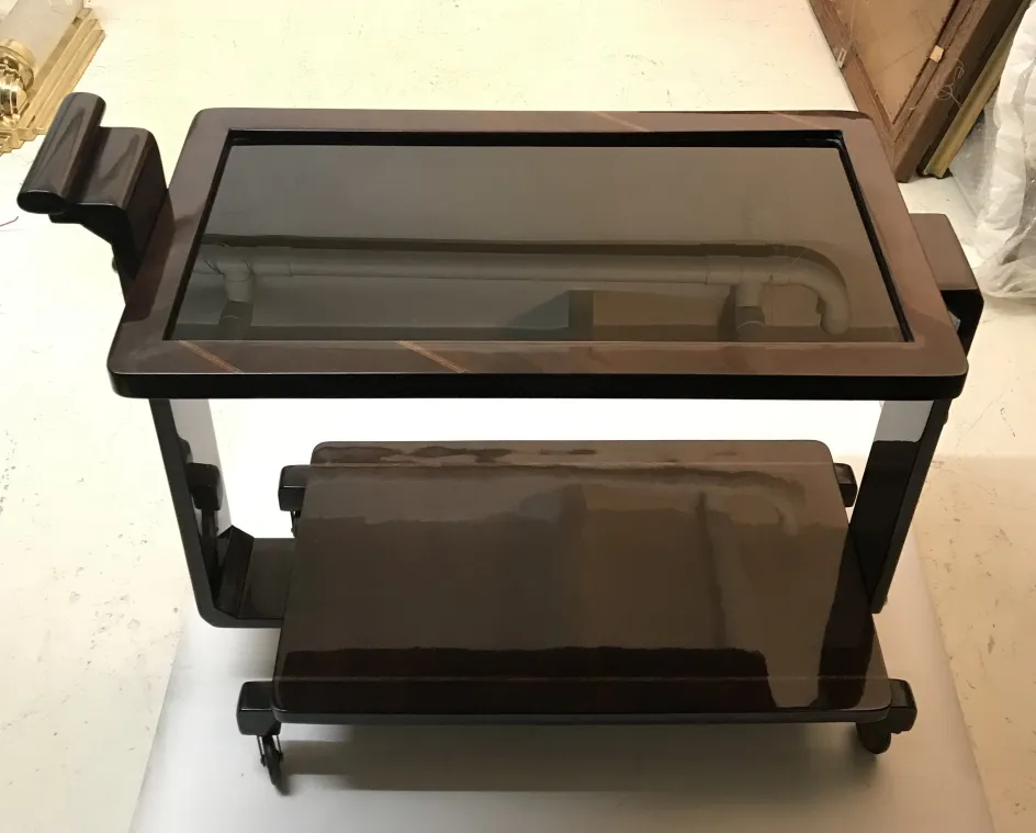 Mesa carrito antigua con superficie de vidrio y ruedas.