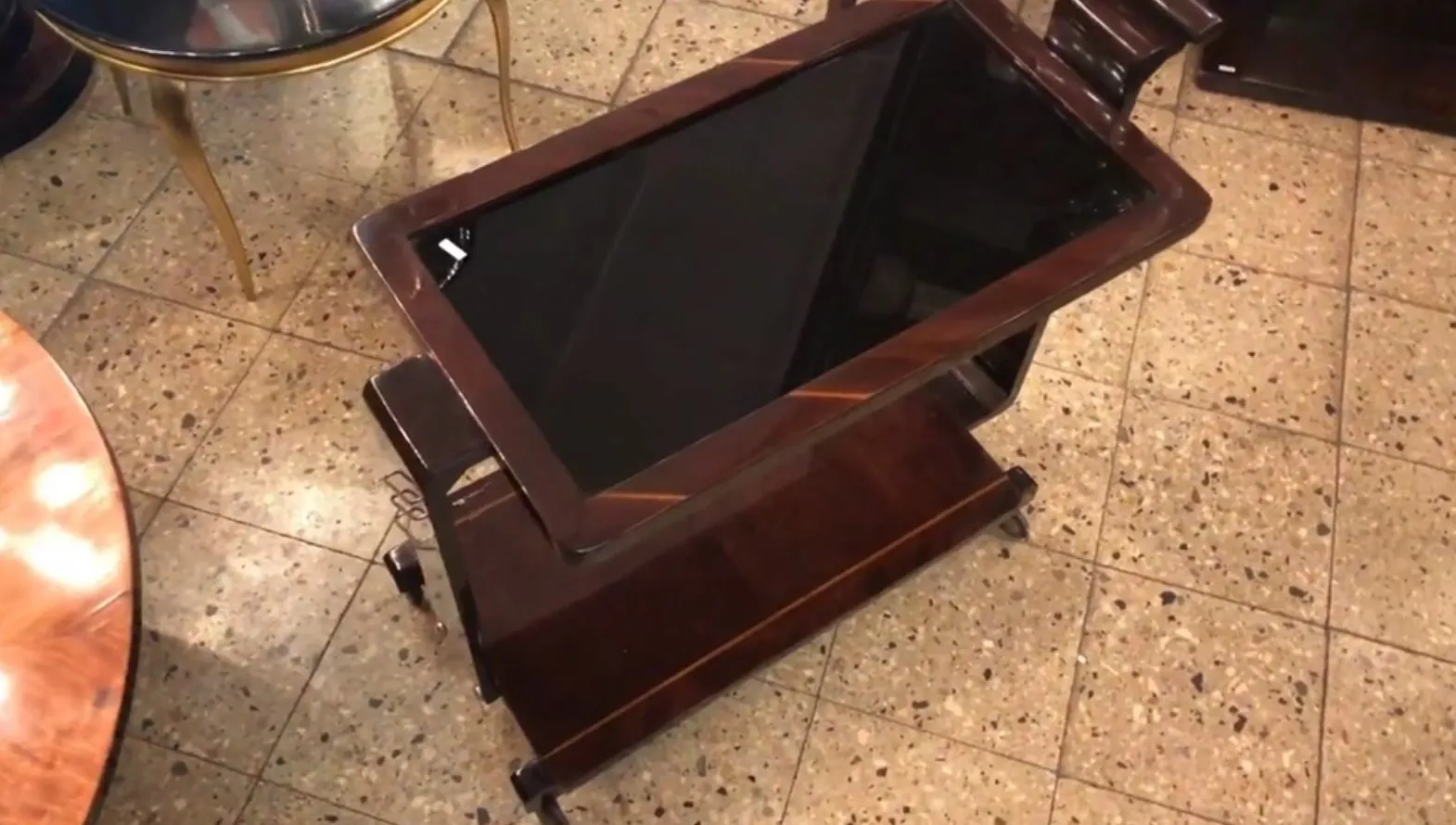 Mesa carrito antigua con superficie de vidrio en ambiente elegante.