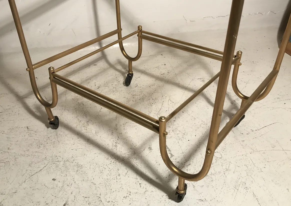 Mesa carrito dorada antigua con ruedas, diseño elegante.