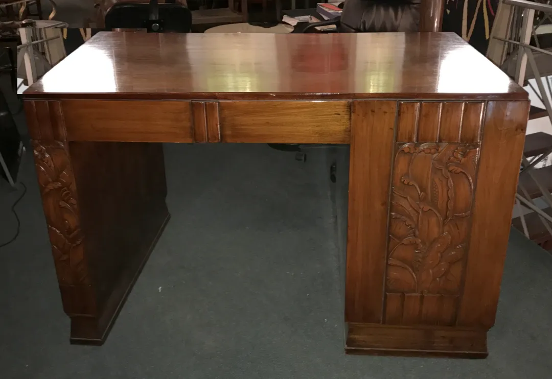 Scrivania antica in legno con sculture decorative sui lati.