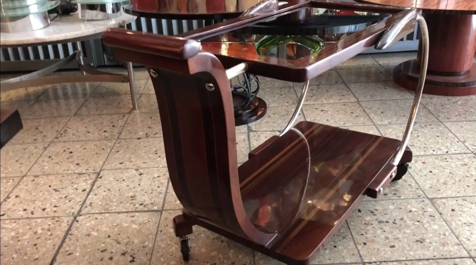 Carrello per cocktail antico, legno scuro con ruote, ambiente elegante.