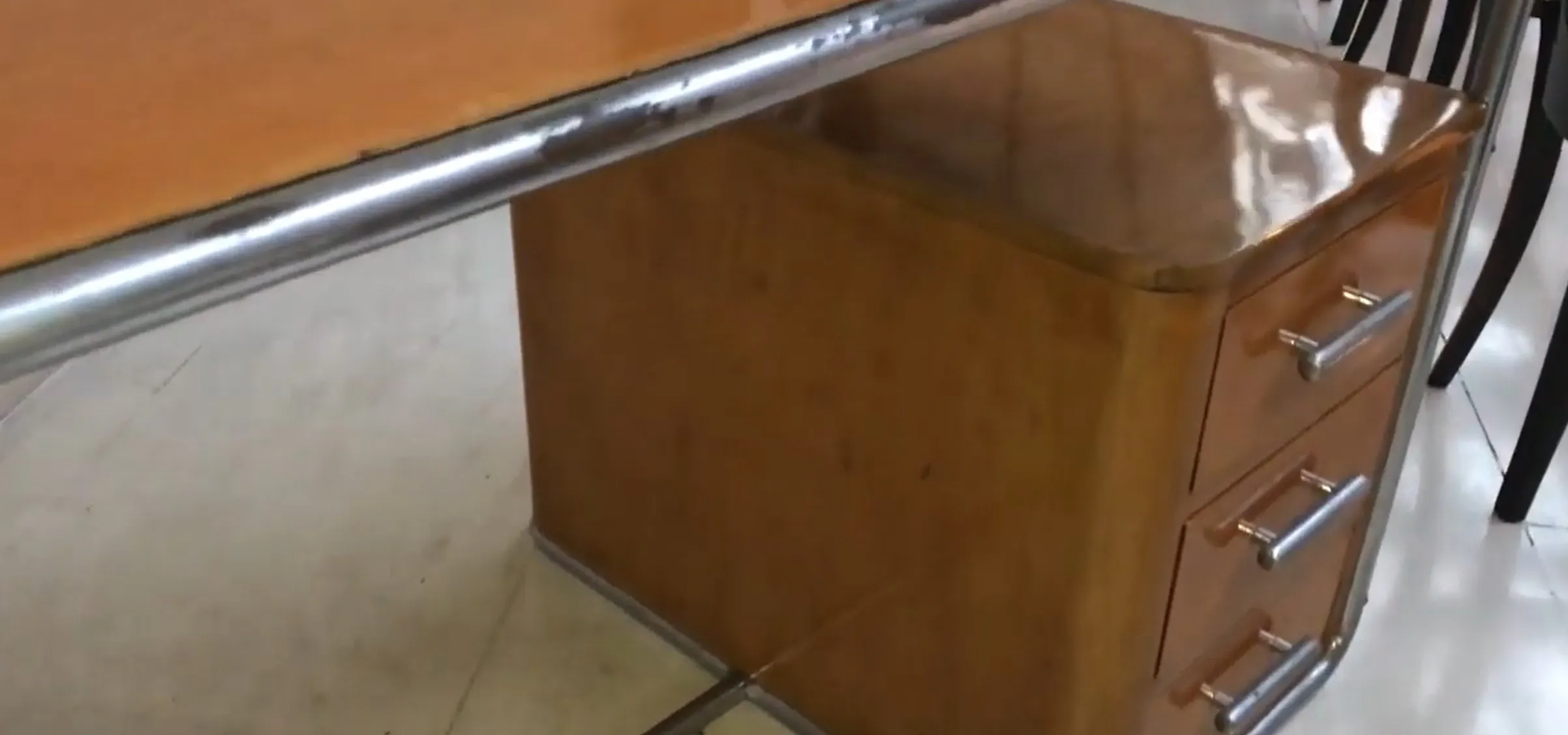 Antiker Holztisch mit zwei Schubladen und Metallelementen, in einem schlichten Umfeld.