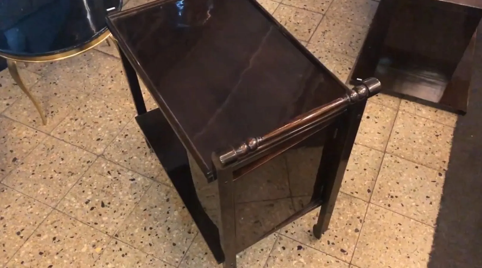 Antique cocktail trolley with a shiny surface and elegant legs. Modern setting.