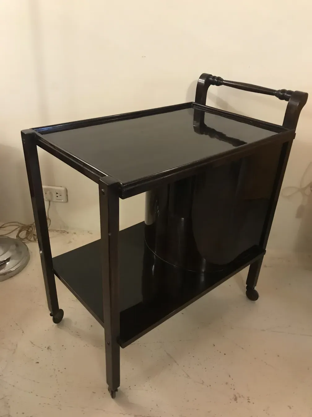 Antiker Cocktailwagen mit zwei Ebenen, dunkles Holz, elegantes Design, neutraler Hintergrund.