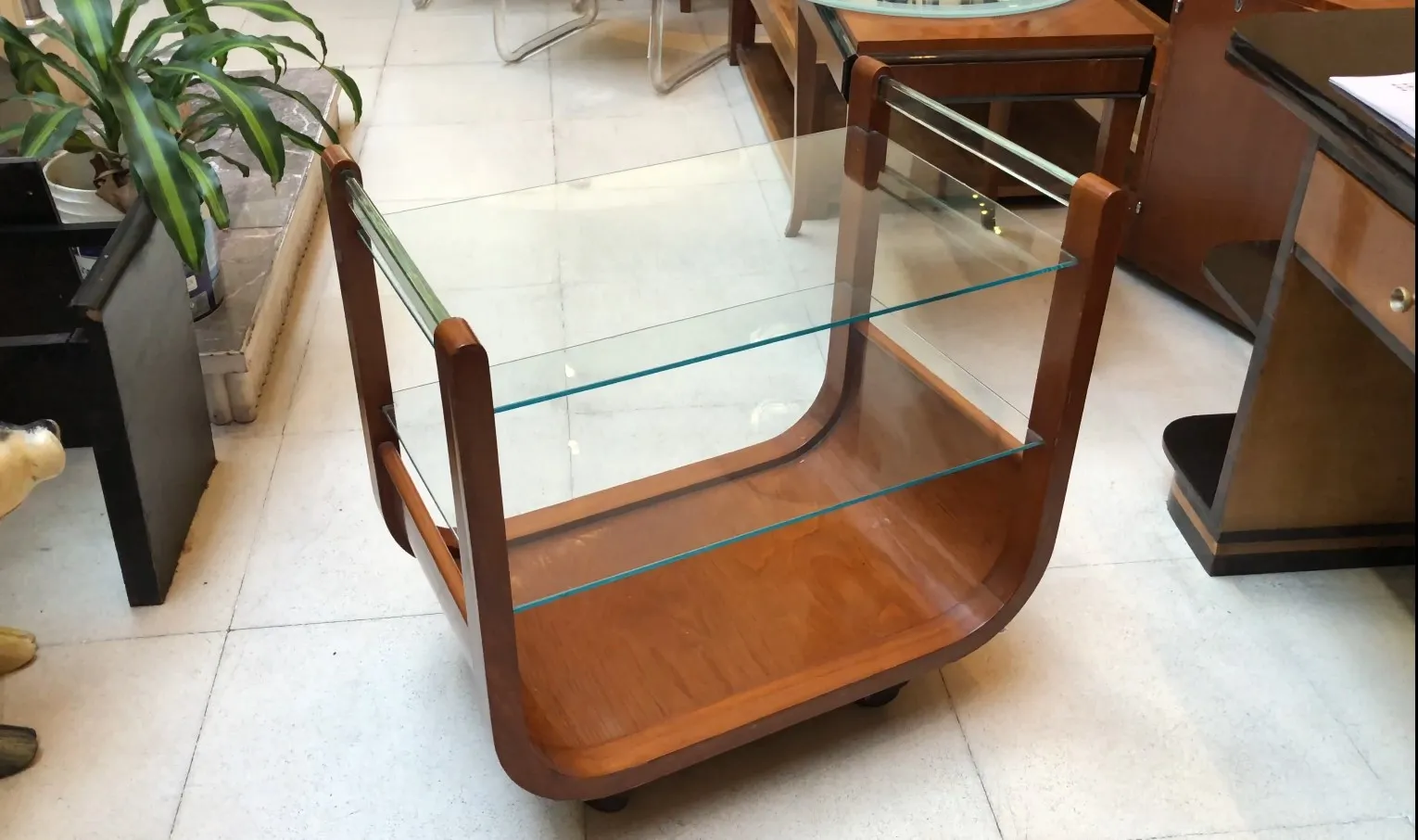 Antique cocktail trolley with glass shelves in a stylish setting.