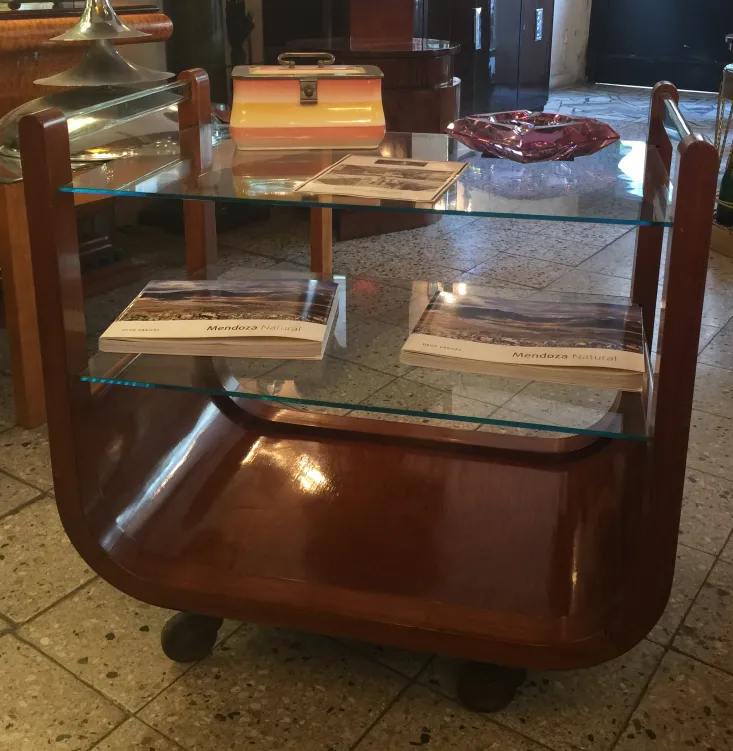 Chariot-bar ancien avec étagères en verre et bois poli dans un cadre classique.