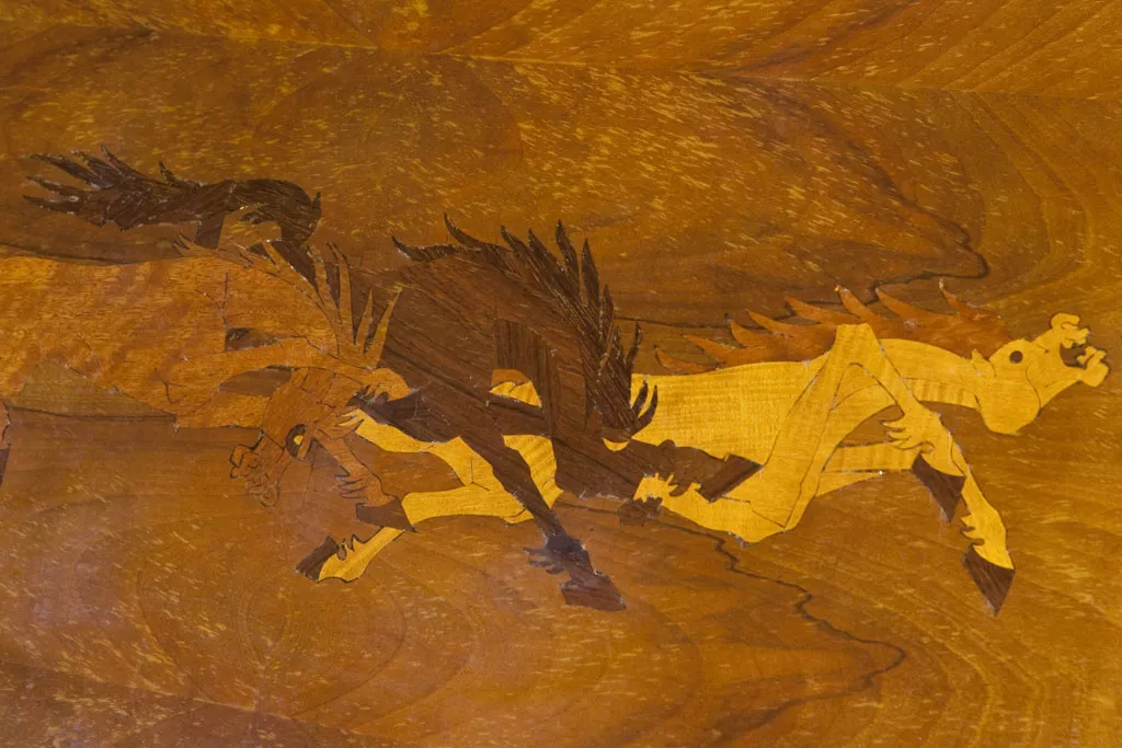 Scrivania antica in legno con design artigianale che rappresenta scene di caccia.