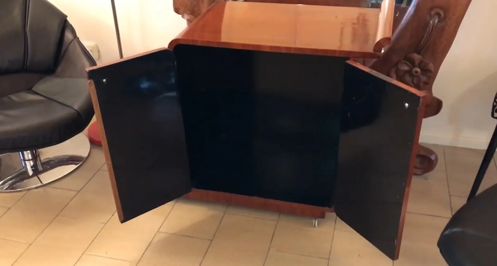 Mesa carrito antigua con puertas negras y acabado brillante.