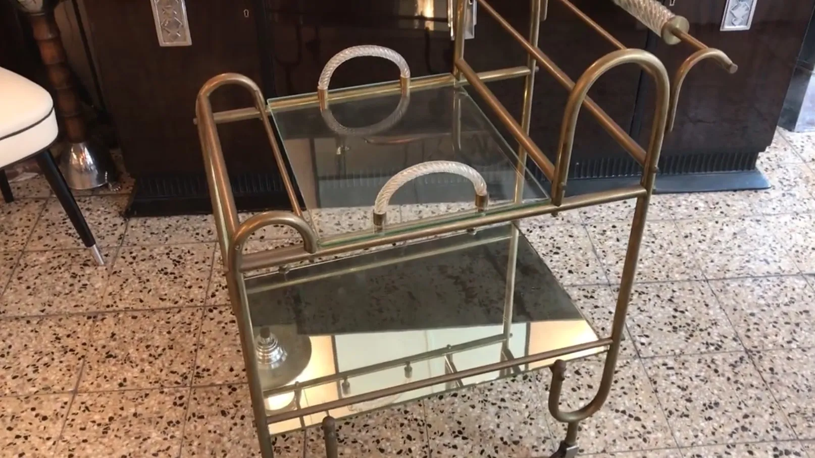 Antique cocktail trolley with gold metal and clear glass, in a stylish environment