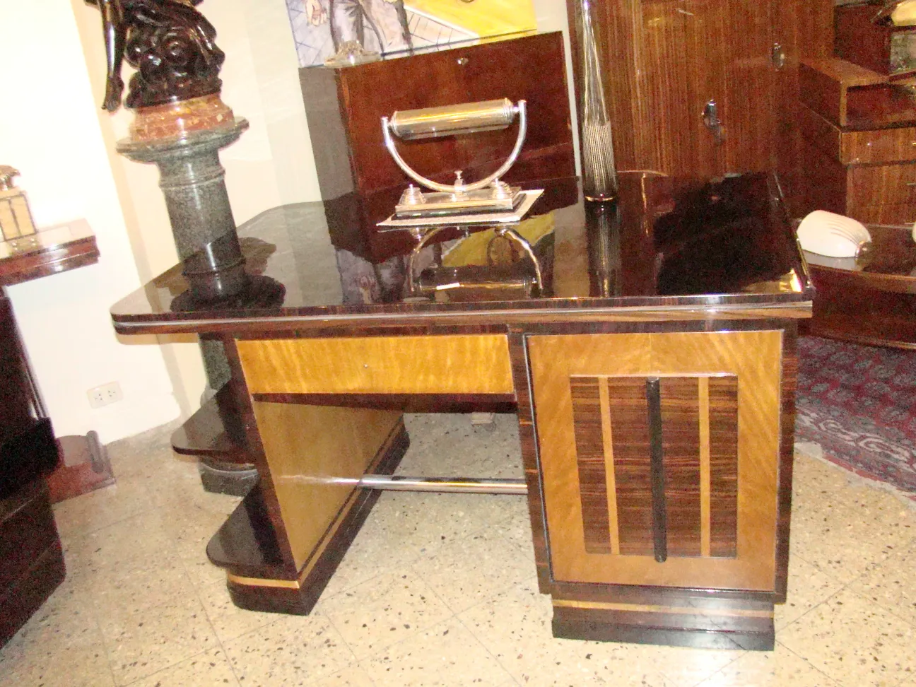 Scrivania antica con design elegante e finiture lucide, circondata da mobili in legno.