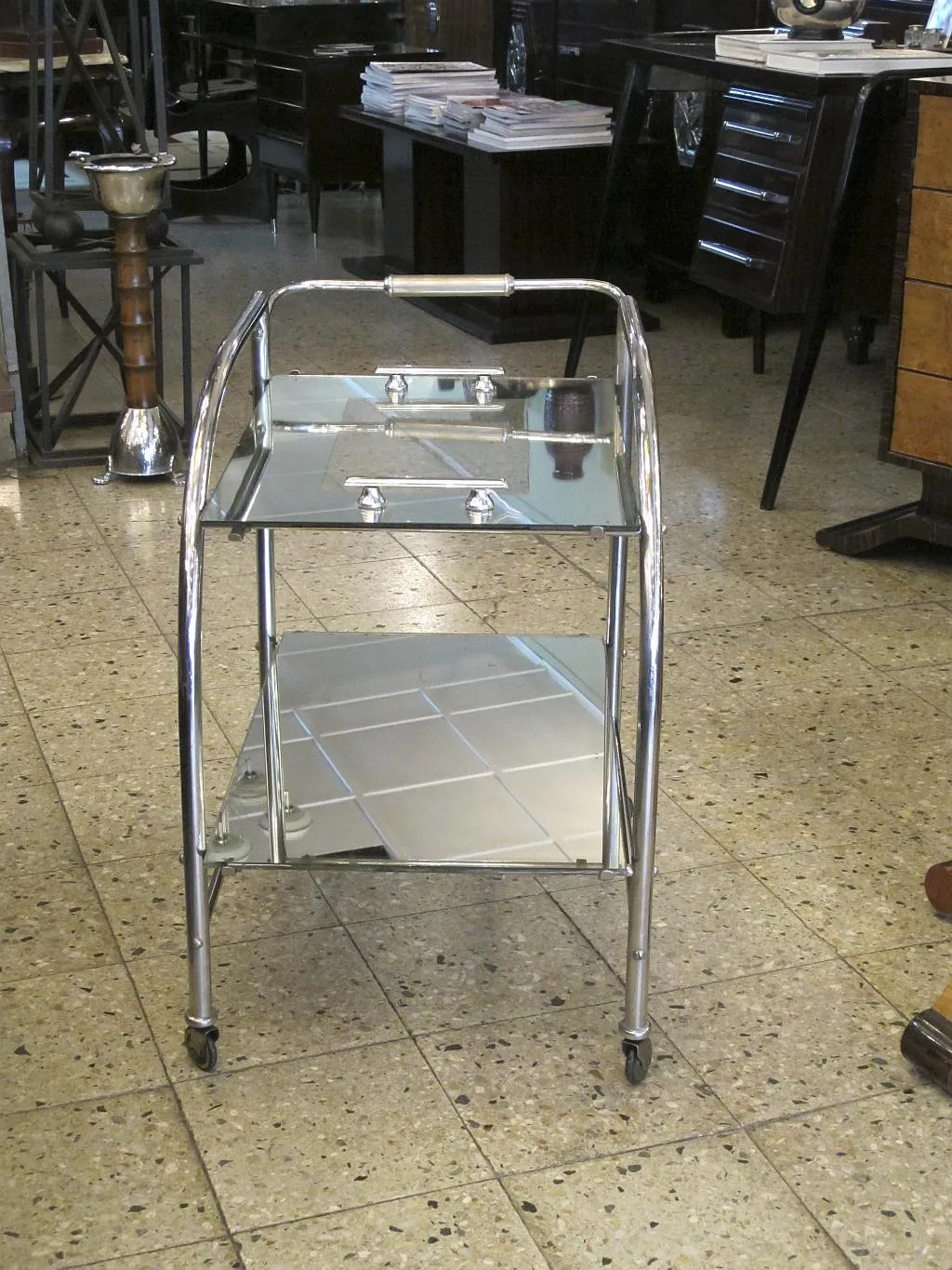 Mesa carrito antigua de dos niveles con ruedas en un ambiente elegante.