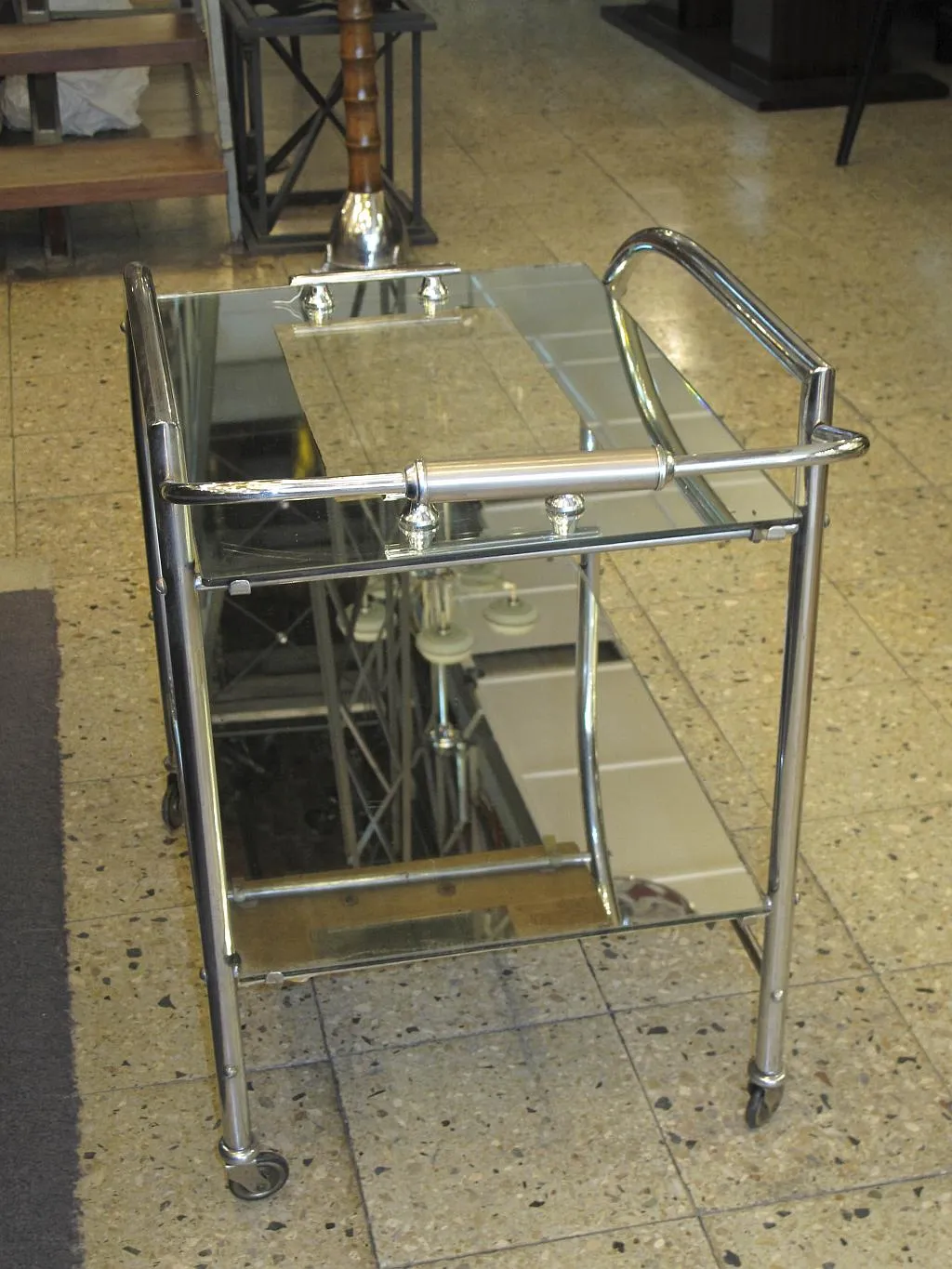 Antique cocktail trolley with metal frame and glass shelves.