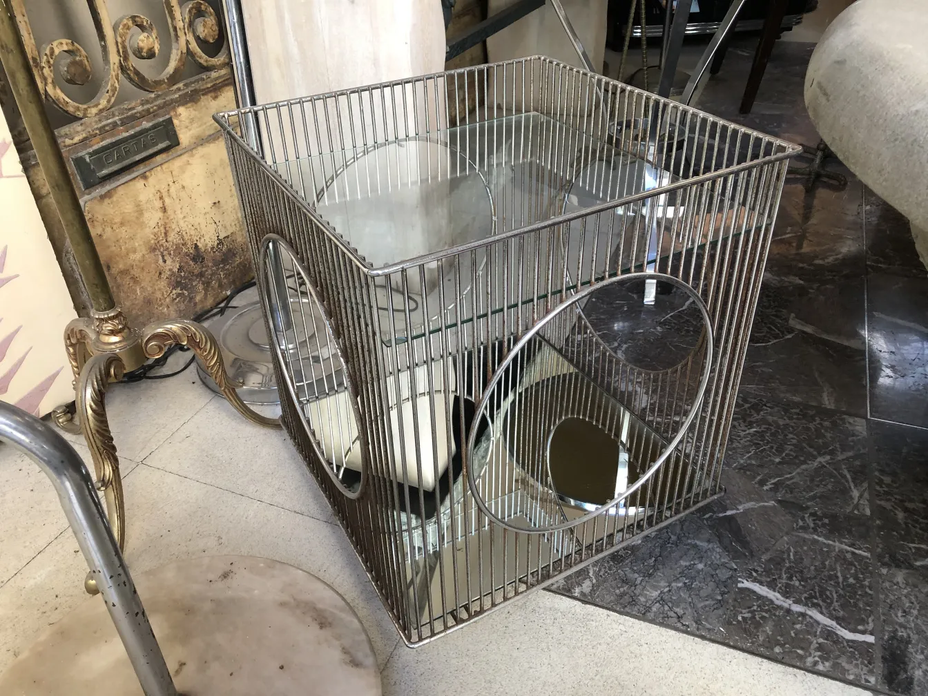 Mesa carrito antigua con detalles metálicos y espejos, ambiente de antigüedades.