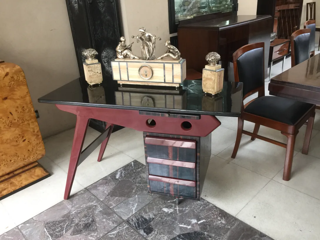Antique desk with a sleek black top and stylish legs, decorated with decorative pieces.