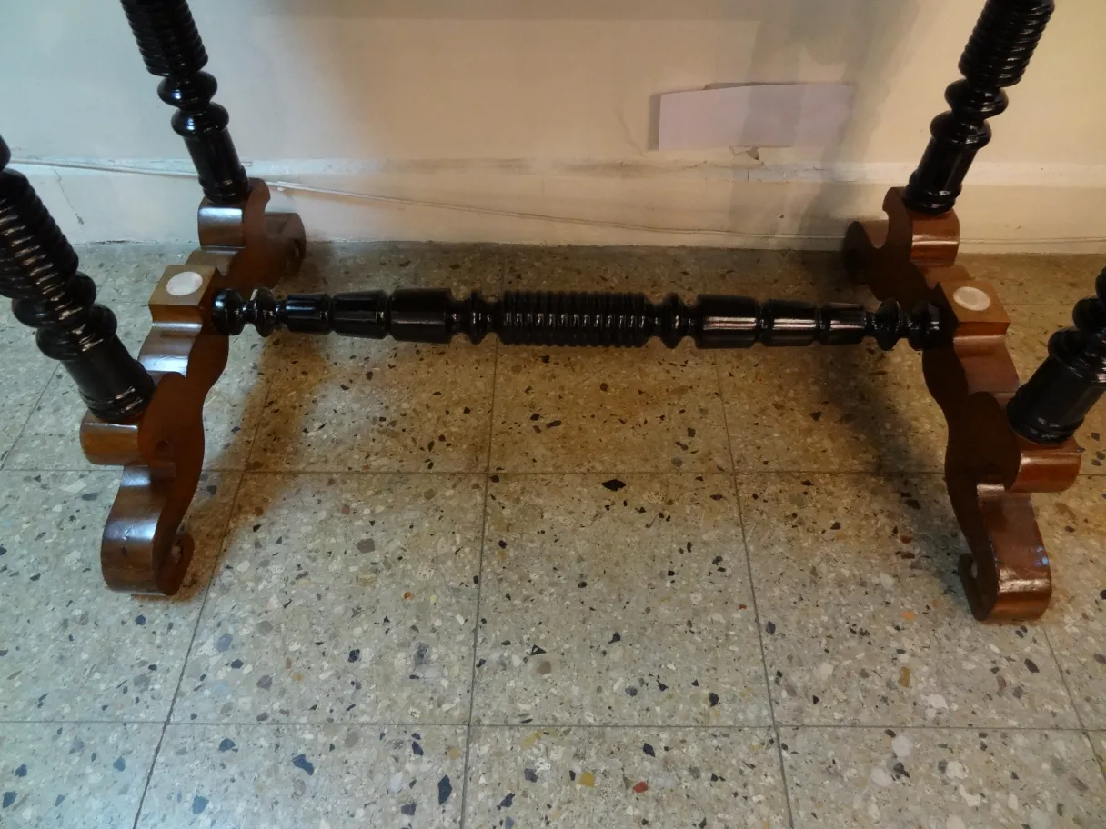 Escritorio antiguo de madera con patas torneadas y soporte decorativo.