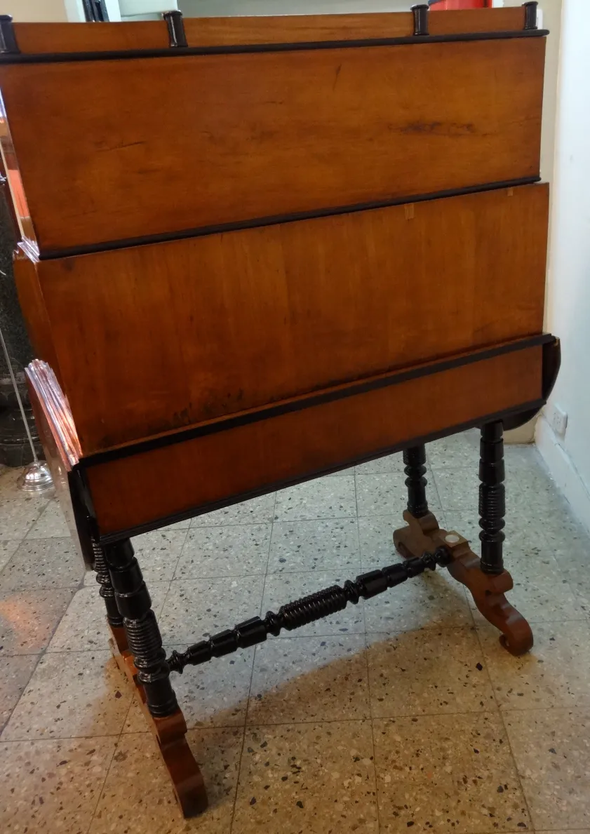 Scrivania antica in legno con un leggio nero, in un ambiente accogliente.