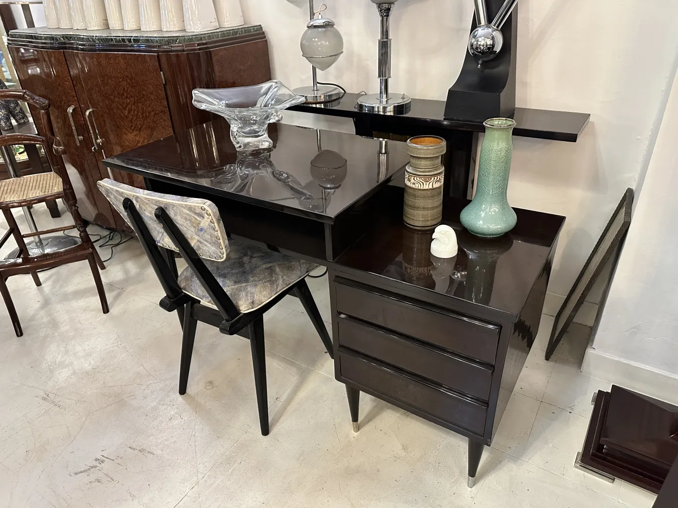 Bureau ancien en bois noir avec une chaise et des décorations.